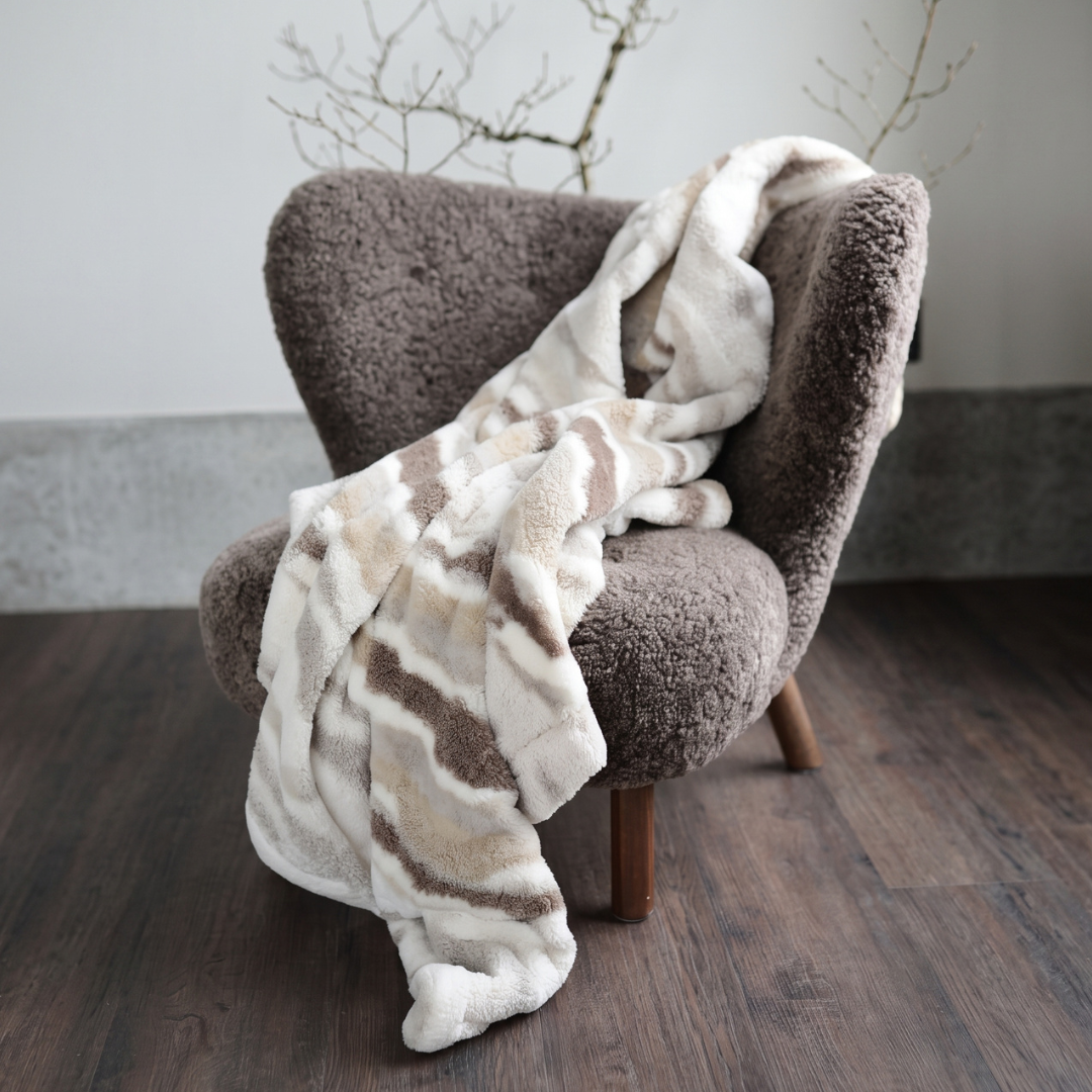 Snygg mönstrad pläd i bruna och beige toner draperad över fåtölj